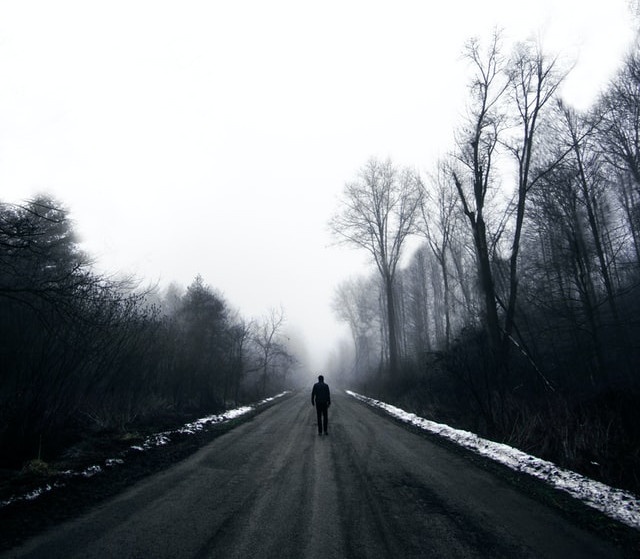 Silhouette of a man standing in the middle of a dark road