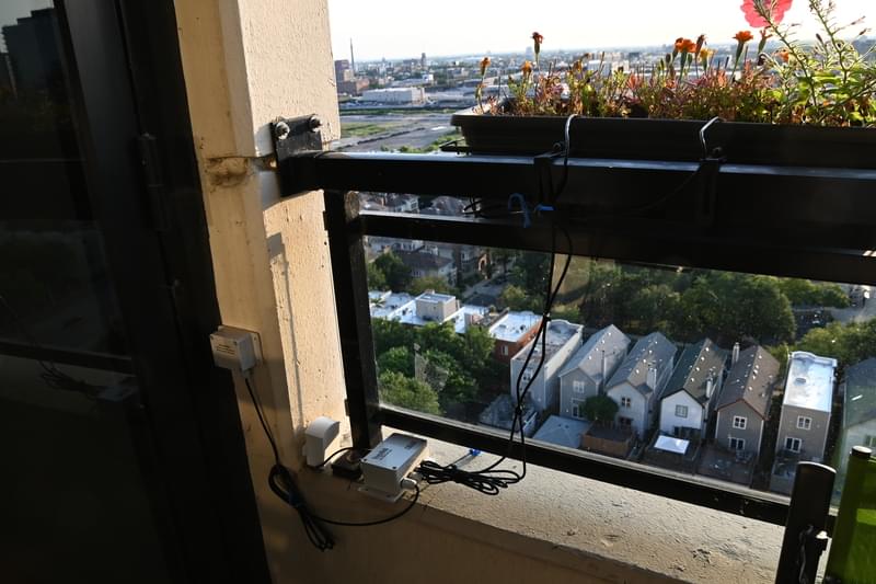 Photo of flower planters hanging from balcony railing with electronic sensors attached