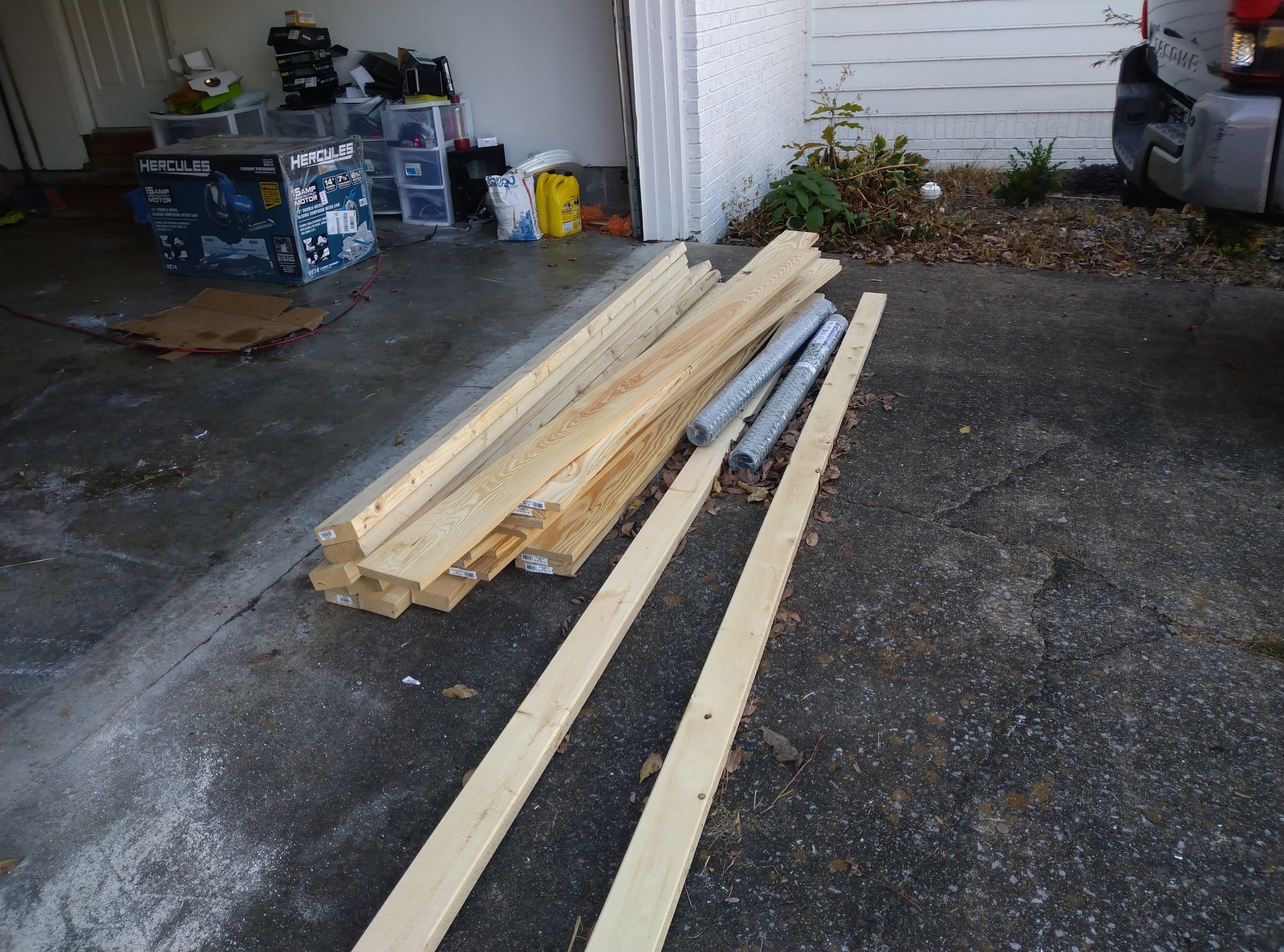 Lumber and building material between open garage and truck bed