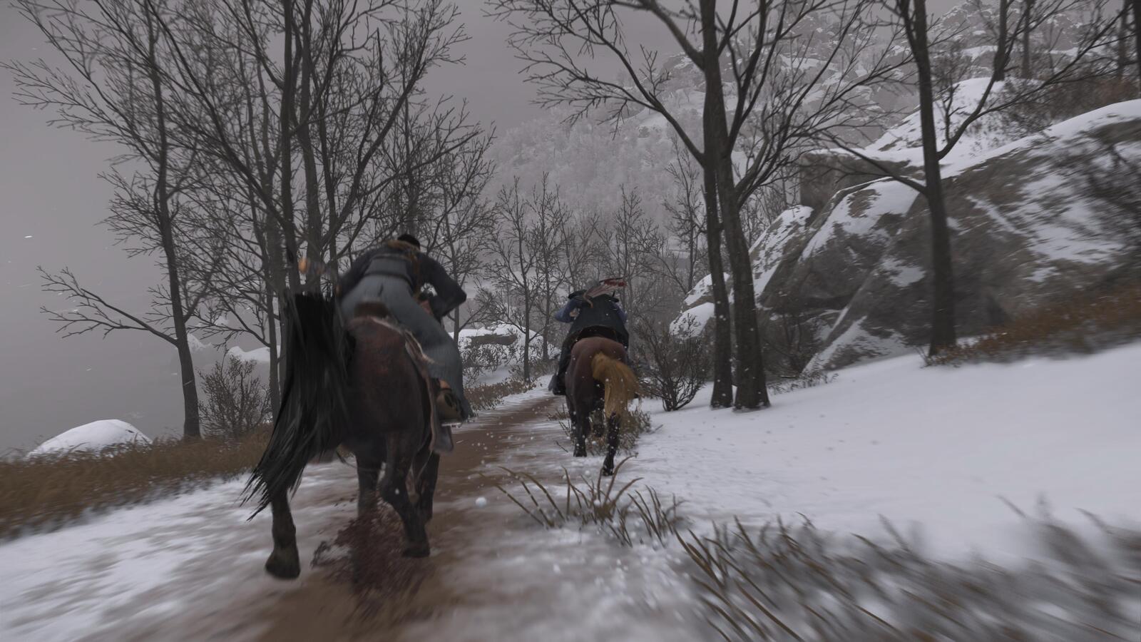 Two people riding on horses through the snow