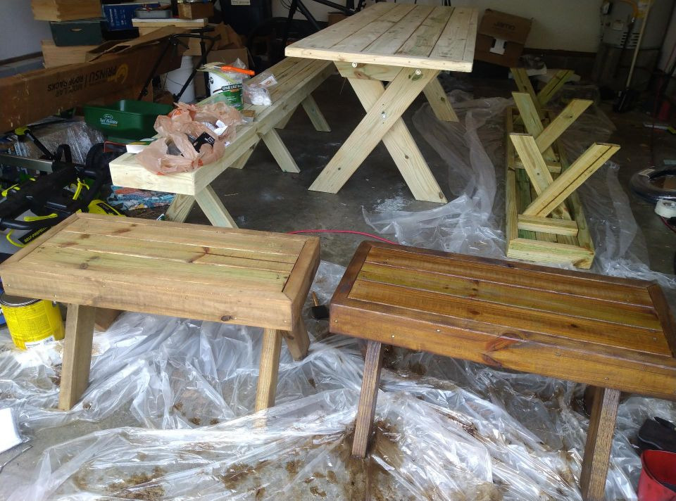 Single coat of stain on the left bench, second coat drying on the right bench, and a long benched turned upside down with pre-stain coating. Table and second long bench untreated.